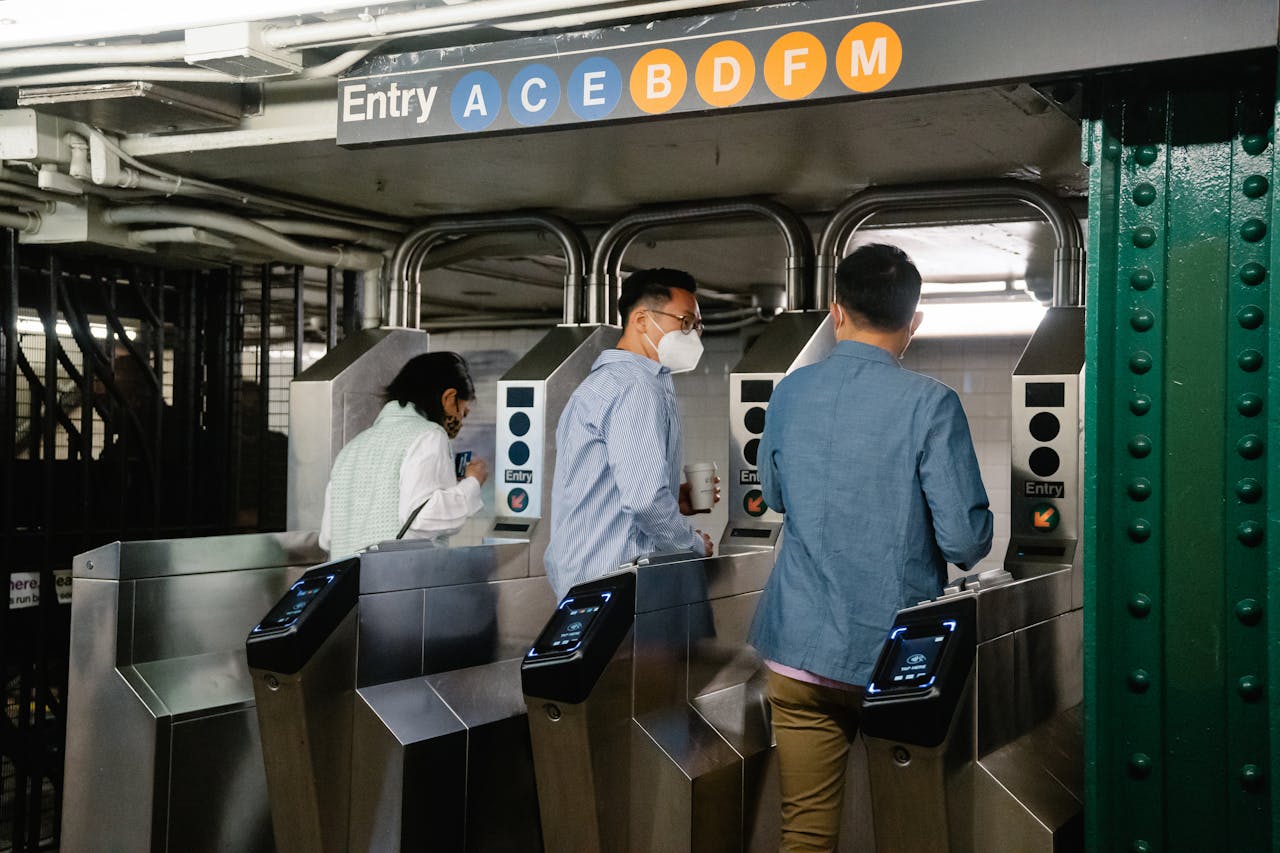 People using turnstiles at a subway station entry in urban setting.